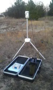 A Geometrics G-856 Magnetometer with a laptop on it sitting in a field.